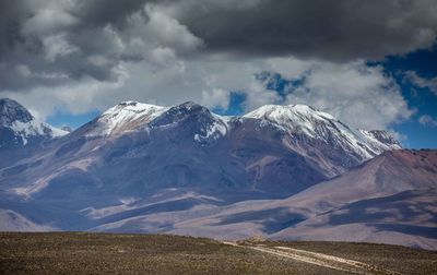 Scenic view of snowcapped mountains against cloudy sky