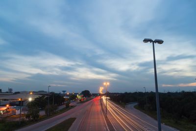 Light trails on road against sky