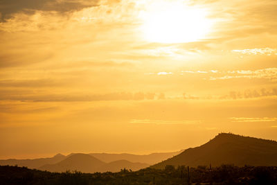 Scenic view of silhouette mountains against orange sky