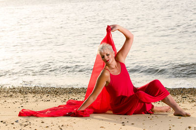 Woman with red scarf sitting on beach