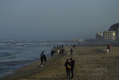 Rear view of people on beach against clear sky