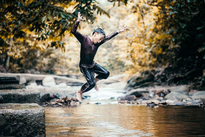 Boy jumping into lake at forest