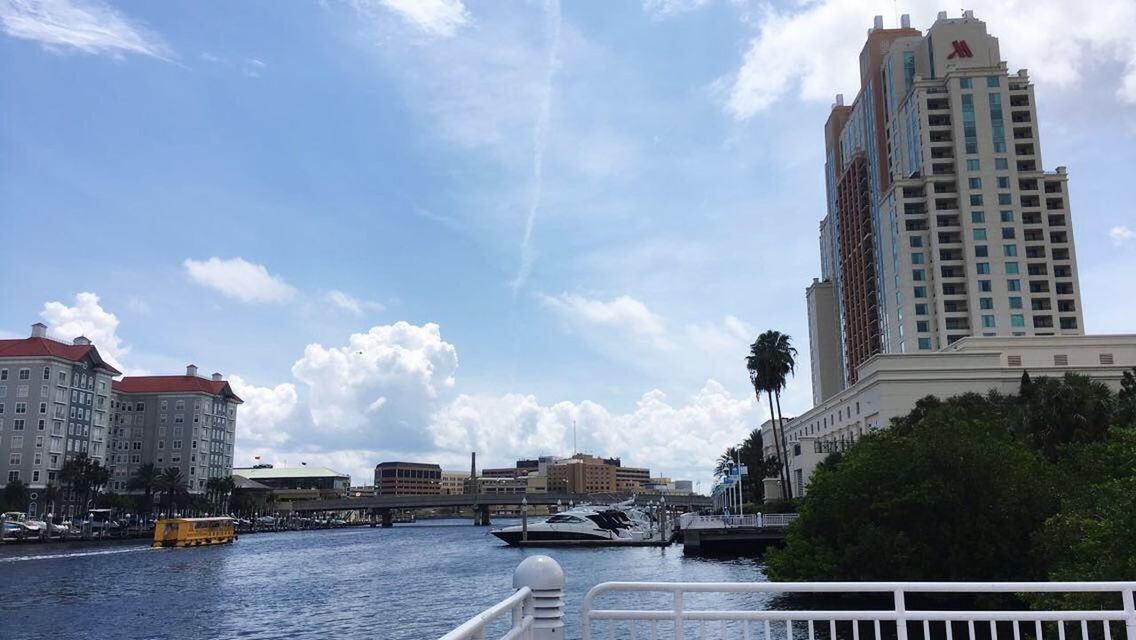 RIVER AMIDST BUILDINGS AGAINST SKY