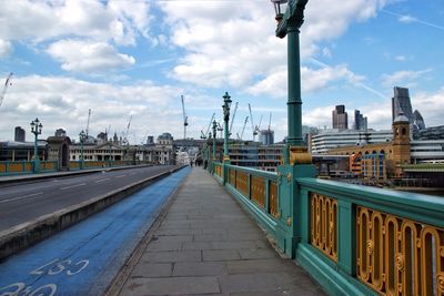 Road by cityscape against sky