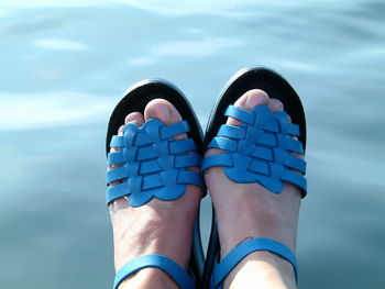 Low angle view of woman wearing blue sandals against lake