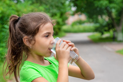 Side view of girl drinking water from glass while looking away