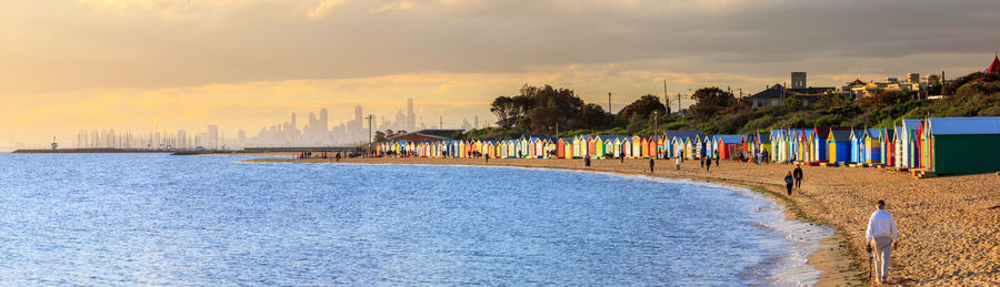 People on beach against sky during sunset