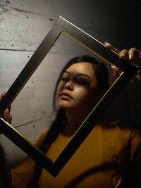 Portrait of young woman holding picture frame