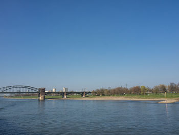 Bridge over river against clear blue sky