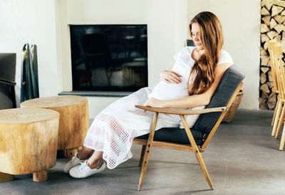 Pregnant woman sitting on chair at home