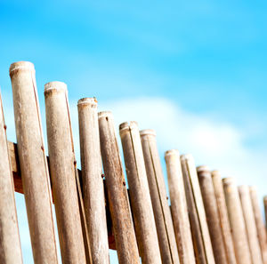 Low angle view of wooden fence against blue sky