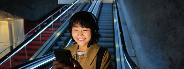 Portrait of young woman sitting on escalator