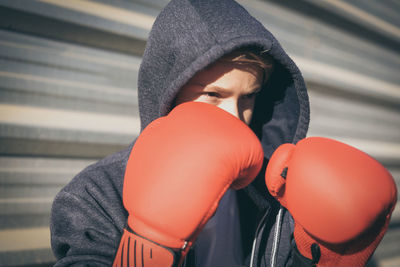 Boy in boxing glove looking away while standing outdoors