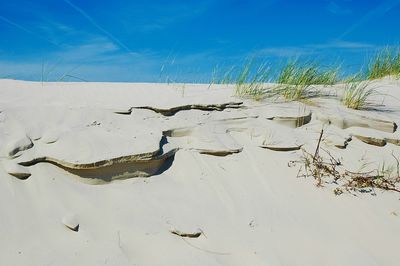 Scenic view of sand dunes at beach against sky