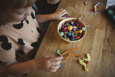 Girl making bead jewelry at table