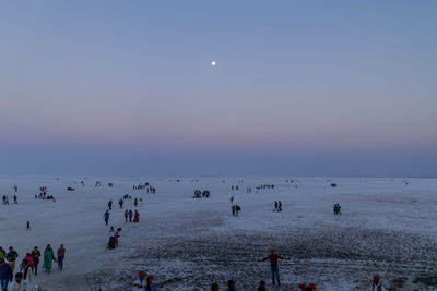 People on beach against sky at dusk