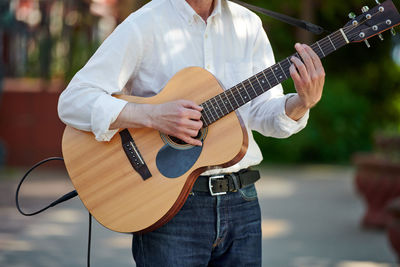 Midsection of man playing guitar