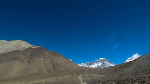 Scenic view of snowcapped mountains against clear blue sky