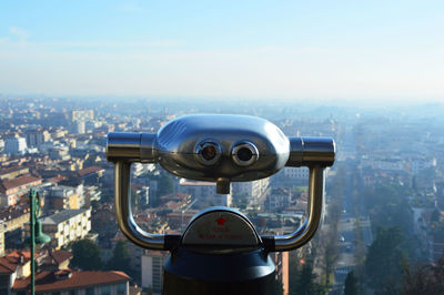 Close-up of coin-operated binoculars against cityscape