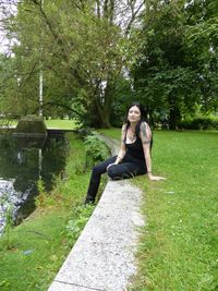 Rear view of woman sitting on tree stump in park