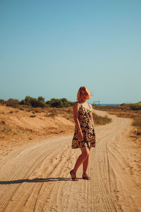 Full length of young woman standing on dirt road