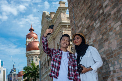 Portrait of young woman standing against buildings in city