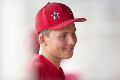 Close-up portrait of teen baseball player in red cap and uniform