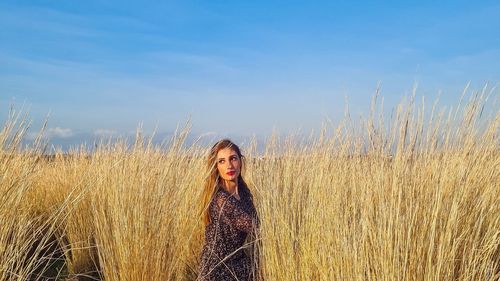 Portrait of woman standing on field against sky