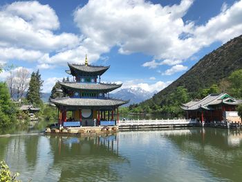 Traditional building by lake against sky