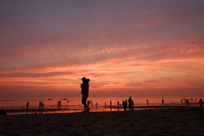 Silhouette people playing on beach against sky during sunset