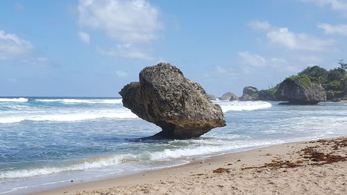 Rock on beach against sky