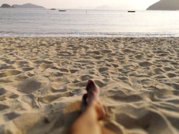 Low section of woman relaxing at beach