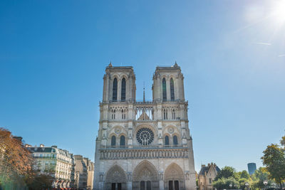 Notre dame de paris - people at famous cathedral with sun and blue sky before fire april 15, 2019