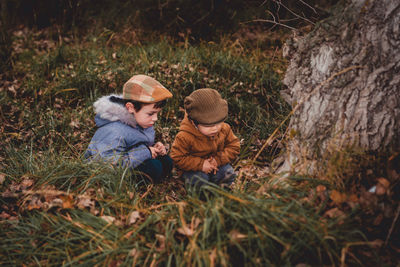 Two children lost in the field looking at a tree in the field with fallen leaves in autumn