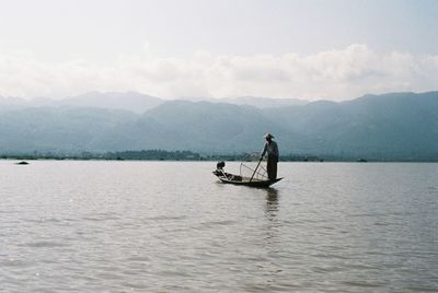 Man on boat in lake against sky