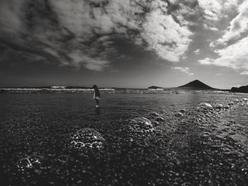 Scenic view of beach against cloudy sky