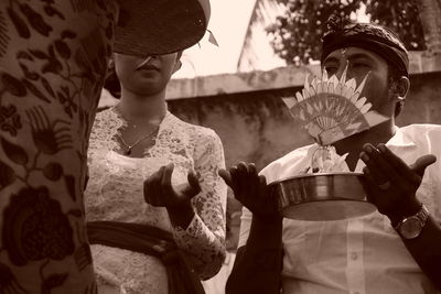 Midsection of woman holding hat standing outdoors