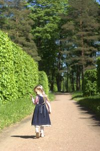 Full length of woman walking on road amidst trees