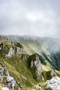 Scenic view of mountains against sky with clouds