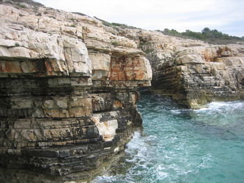 Rock formations by sea against sky