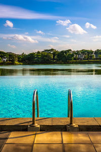 Swimming pool by lake against sky