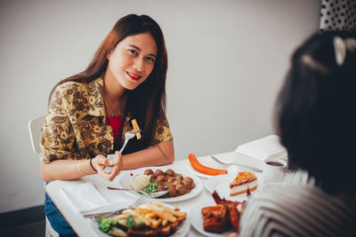 Young woman sitting on table at home