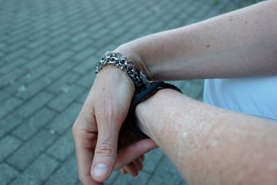 Cropped hand of man wearing bracelet on footpath