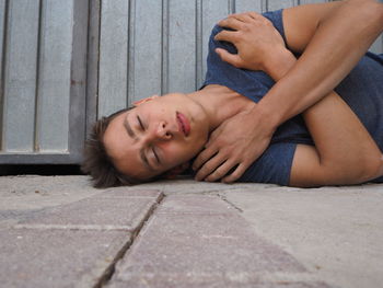 Young man sleeping on footpath
