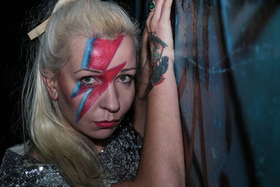 Portrait of young woman with face paint by wall