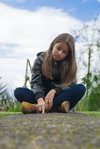 View of girl sitting on footpath
