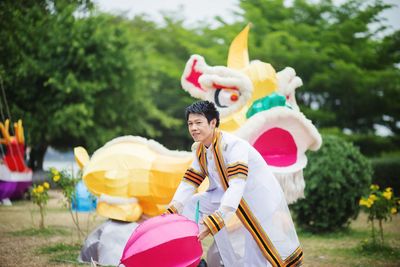 Man in traditional clothing holding toy while standing at park
