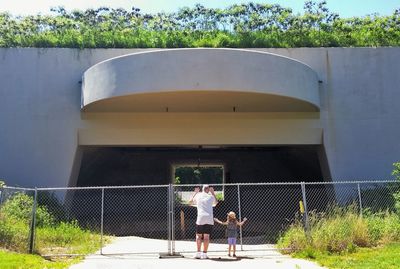 Two people standing at fence against built structure