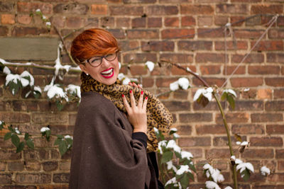 Portrait of young woman against brick wall