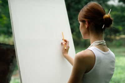 Full length portrait of woman standing against wall